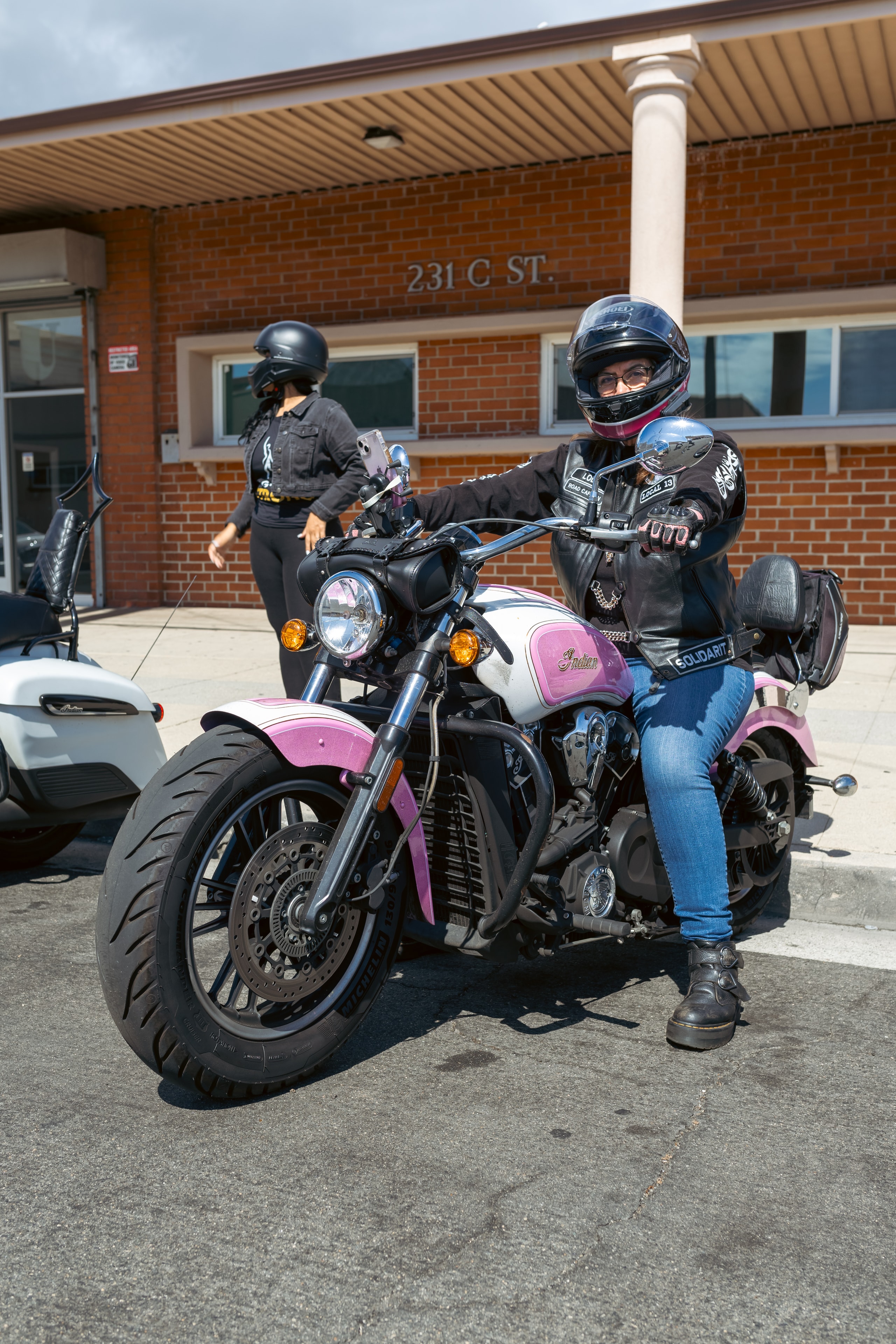 Riders posing on motorcycle outside building